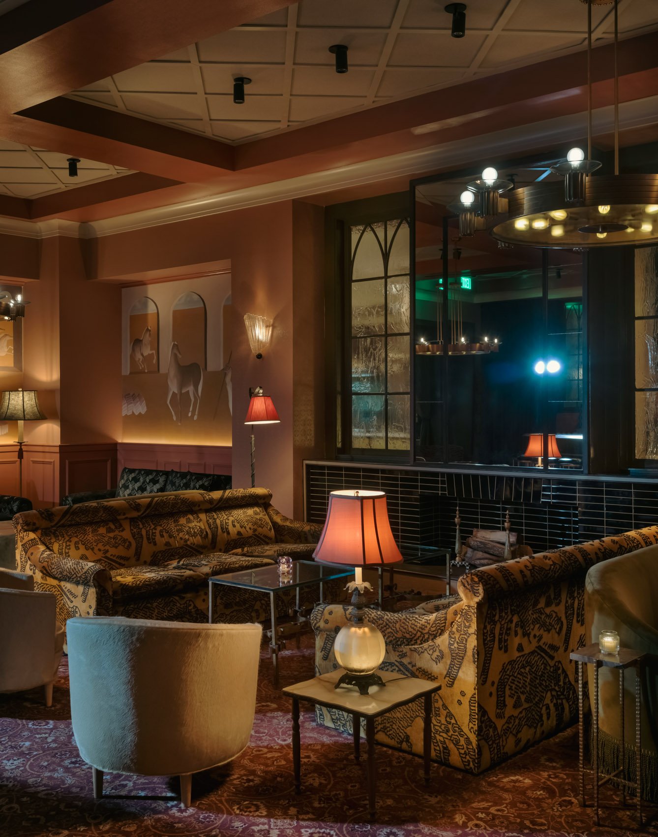 A lounge at Il Premio with patterned sofas, table lamps and a coffered ceiling