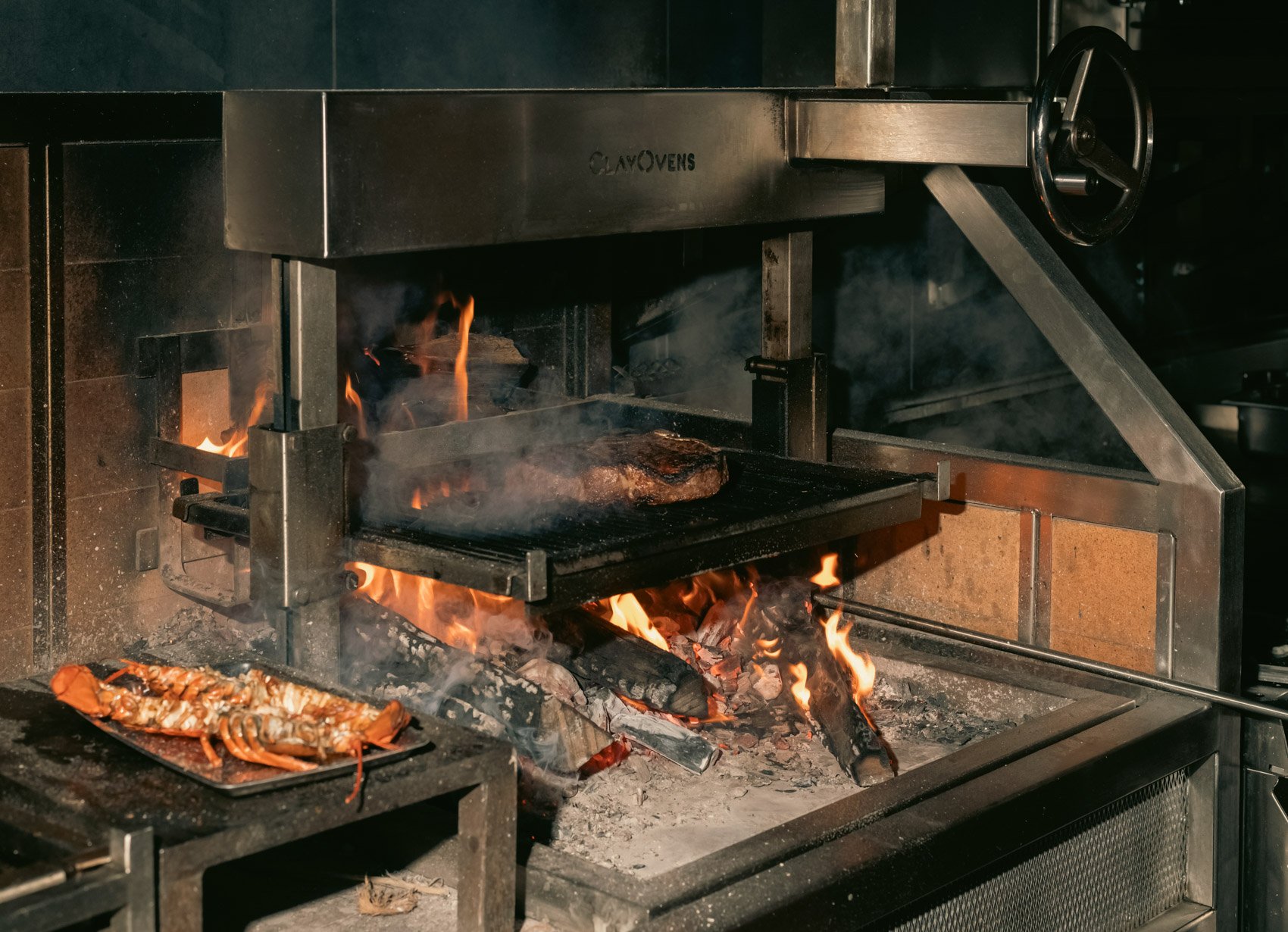 Steaks and seafood cooking over an open wood fire in the Il Premio kitchen