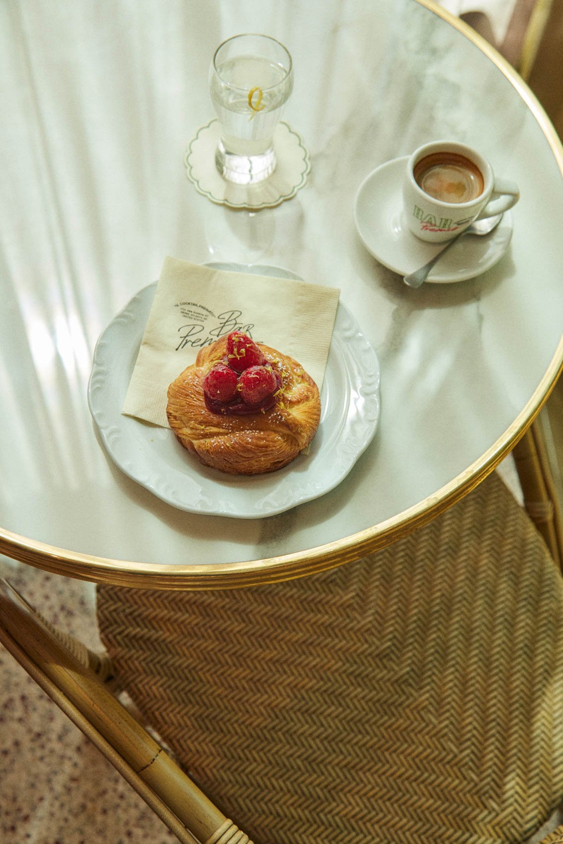 A pastry and an espresso on a marble cafe table at Bar Premio
