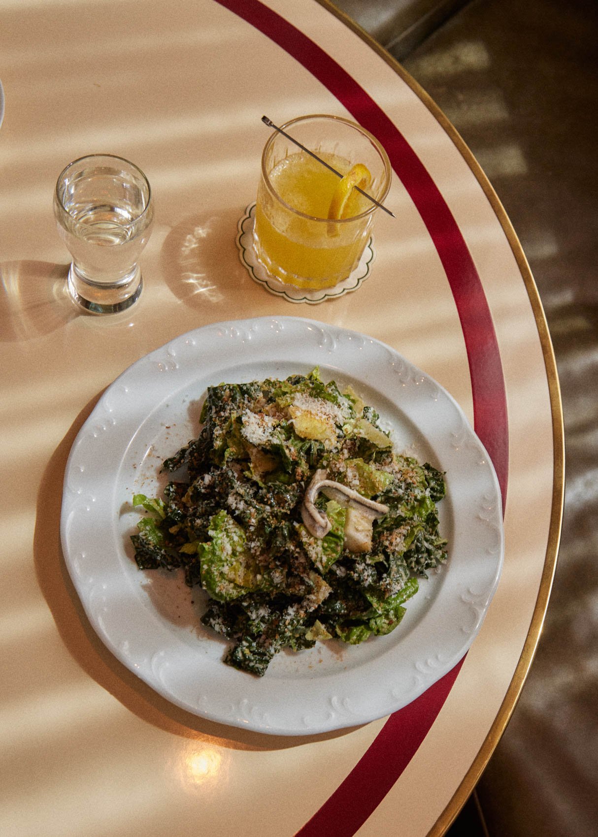 A chopped salad and a citrus cocktail on a cafe table at Bar Premio