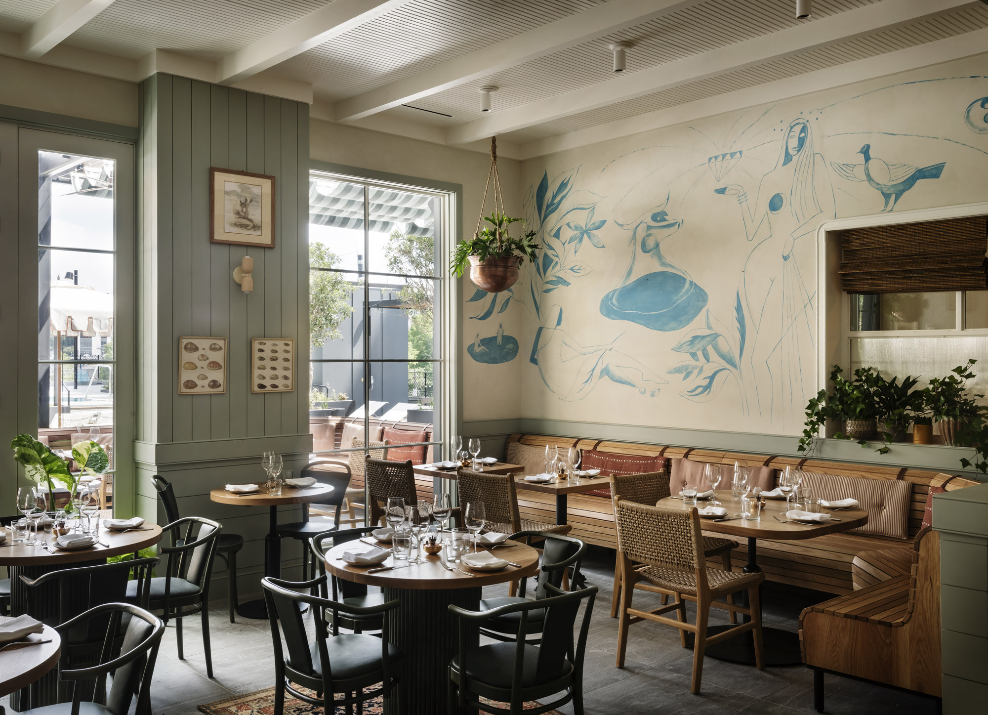 Elektra’s dining room with a blue mural, rattan chairs and leather banquettes